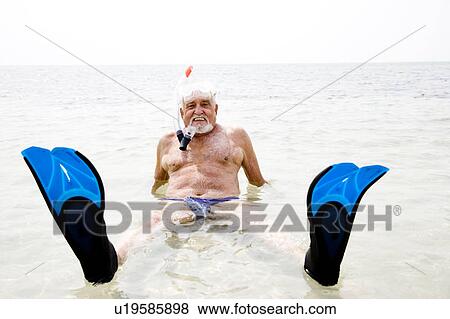 Stock Photo - Senior man with snorkel gear and flippers at the beach . Fotosearch