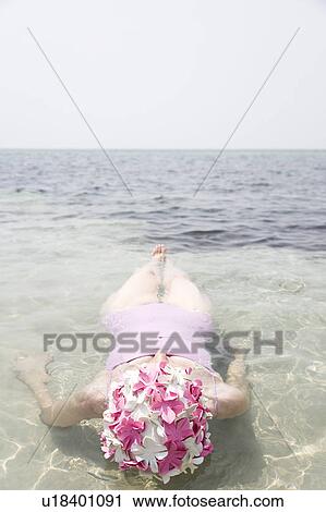 Stock Image - Senior woman in a swimming hat, swimming in the ocean . Fotosearch