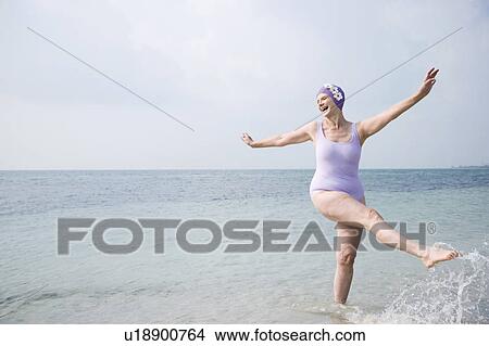 Senior woman in a swimsuit and swimming hat, at the beach View Large Photo Image Picture - Senior woman in a swimsuit and swimming hat, at the beach . Fotosearch