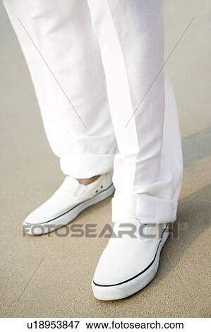 Stock Photo - close up of a man's legs and feet on a beach. Fotosearch