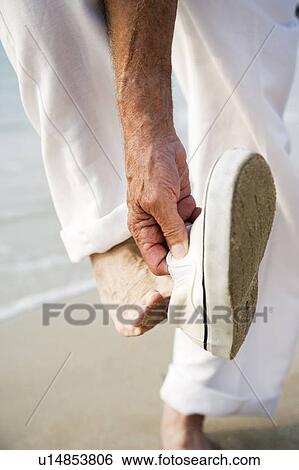 Close up of a senior man putting on his shoes on a beach View Large Photo Image Stock Photograph - Close up of a senior man putting on his shoes on a beach. Fotosearch