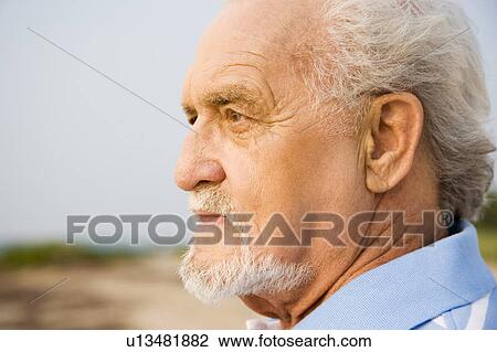 Portrait of a senior man standing on a beach looking thoughtful View Large Photo Image Stock Image - Portrait of a senior man standing on a beach looking thoughtful. Fotosearch
