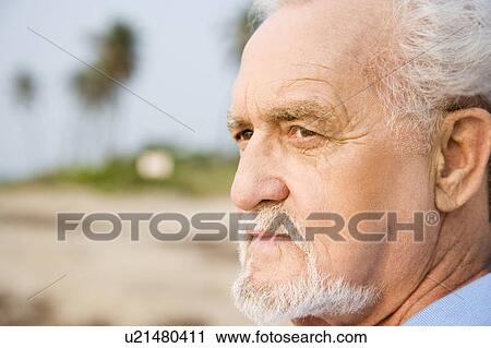 Portrait of a senior man standing on a beach looking thoughtful View Large Photo Image Stock Image - Portrait of a senior man standing on a beach looking thoughtful . Fotosearch