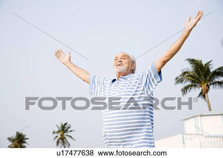 Portrait of a senior man standing on a beach with arms outstretched View Large Photo Image Stock Photo - Portrait of a senior man standing on a beach with arms outstretched. Fotosearch