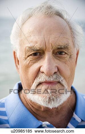 Stock Photography - Portrait of a senior man standing on a beach looking thoughtful. Fotosearch