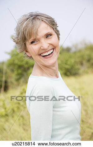 Picture - Portrait of a smiling senior woman in a tropical dune setting . Fotosearch