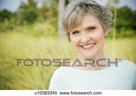 Stock Photography - Portrait of a smiling senior woman in a tropical dune setting . Fotosearch