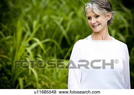 Portrait of a smiling senior woman in front of tropical foliage View Large Photo Image Stock Photo - Portrait of a smiling senior woman in front of tropical foliage . Fotosearch