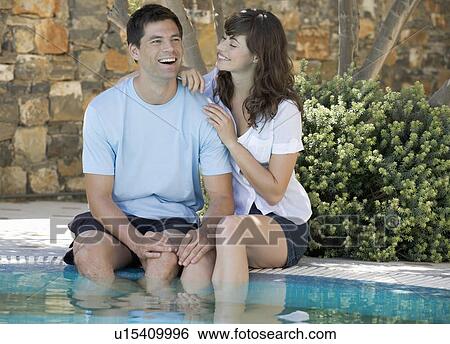 Stock Photograph - A couple relaxing by a pool. Fotosearch