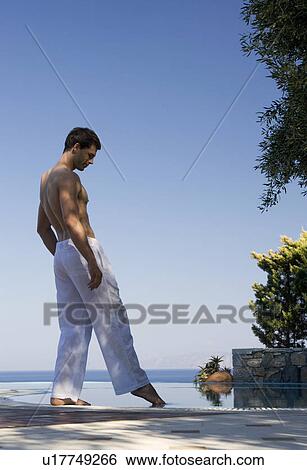 A man standing by a pool View Large Photo Image Stock Photograph - A man standing by a pool. Fotosearch