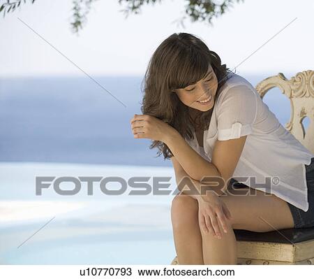 Stock Image - A woman relaxing by a pool. Fotosearch