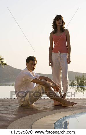Stock Image - A couple relaxing by a pool. Fotosearch