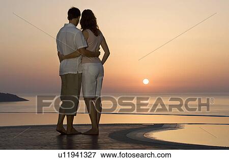 Stock Photo - A couple watching the sun set. Fotosearch