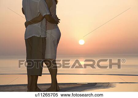 A couple watching the sun set View Large Photo Image Stock Photography - A couple watching the sun set. Fotosearch