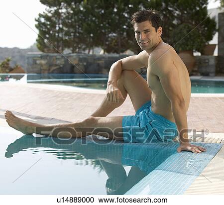 Stock Image - A man relaxing at the edge of a pool. Fotosearch