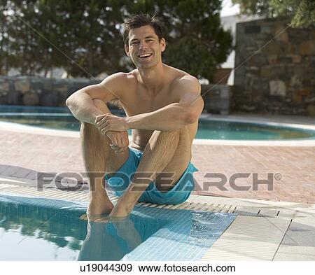 Stock Photo - A man relaxing at the edge of a pool. Fotosearch