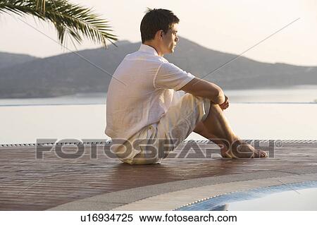Stock Photography - A man sitting by a pool. Fotosearch