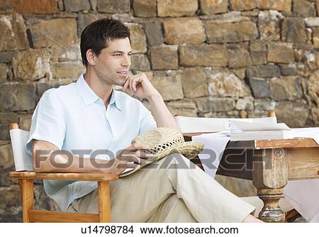 Picture - A man reading a book at a table. Fotosearch