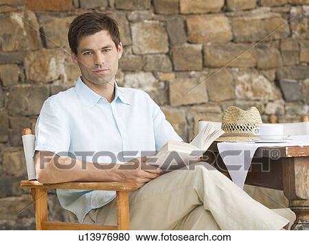 Stock Image - A man reading a book at a table. Fotosearch