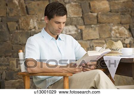 A man reading a book at a table View Large Photo Image Stock Photo - A man reading a book at a table. Fotosearch