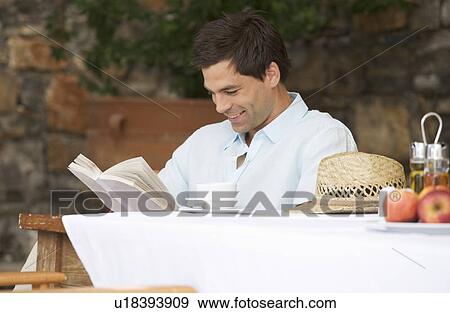 A man reading a book at a table View Large Photo Image Stock Photo - A man reading a book at a table. Fotosearch