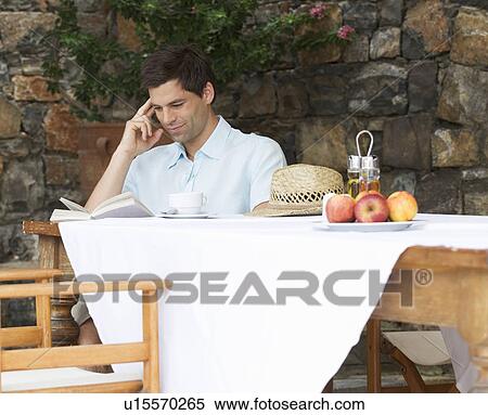 A man reading a book at a table View Large Photo Image Stock Photography - A man reading a book at a table. Fotosearch