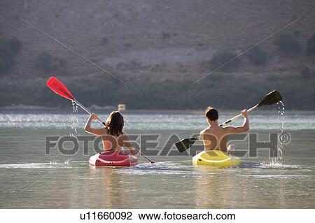 A couple canoeing on a lake View Large Photo Image Stock Image - A couple canoeing on a lake. Fotosearch
