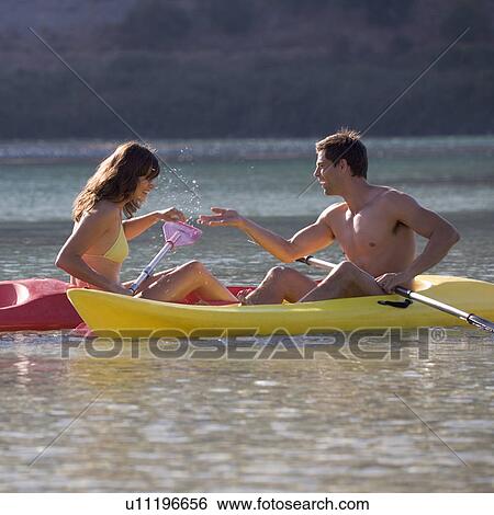 Stock Photograph - A couple canoeing on a lake. Fotosearch