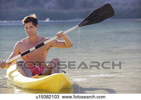 Stock Image - A man canoeing on a lake. Fotosearch