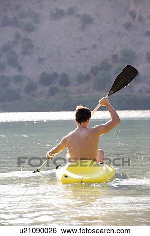 Stock Photograph - A man canoeing on a lake. Fotosearch