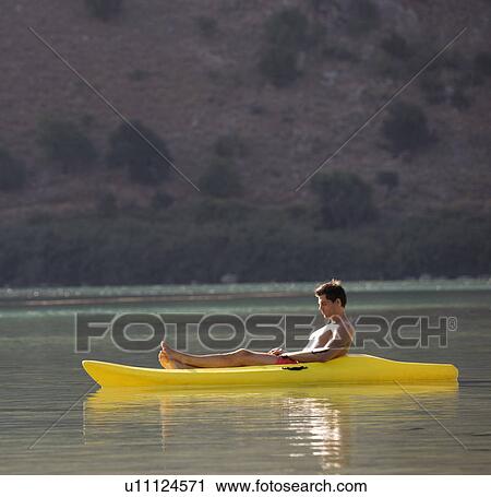 Stock Image - A man relaxing in a canoe. Fotosearch