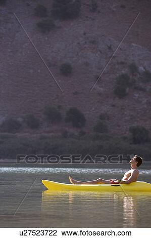 Stock Image - A man relaxing in a canoe. Fotosearch