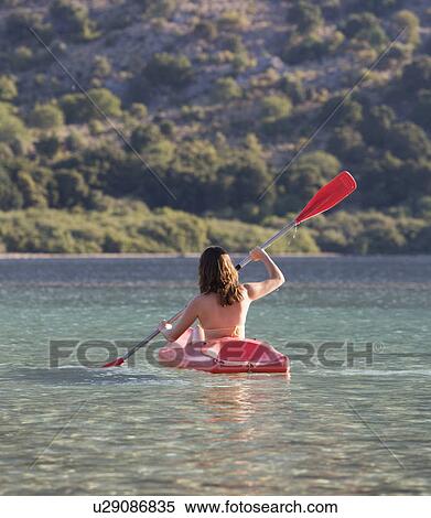 A woman canoeing on a lake View Large Photo Image Stock Photography - A woman canoeing on a lake. Fotosearch