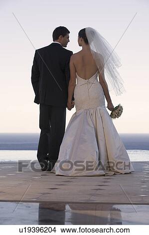 A bride and groom holding hands View Large Photo Image Picture - A bride and groom holding hands. Fotosearch