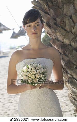 Stock Image - A bride standing on a beach. Fotosearch
