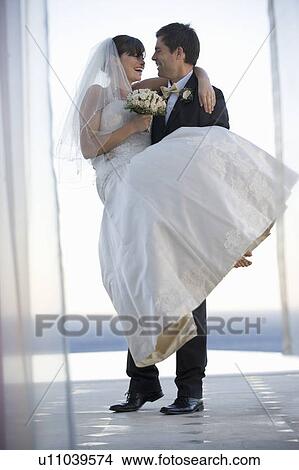 A groom carrying his bride View Large Photo Image Picture - A groom carrying his bride. Fotosearch