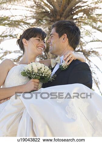 A groom carrying his bride View Large Photo Image Stock Image - A groom carrying his bride. Fotosearch