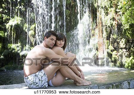 A couple sitting by a waterfall View Large Photo Image Stock Image - A couple sitting by a waterfall. Fotosearch