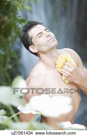 Picture - A man standing in a waterfall. Fotosearch