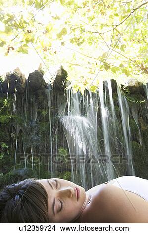 Picture - A woman relaxing by a waterfall. Fotosearch