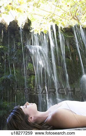 A woman relaxing by a waterfall View Large Photo Image Stock Photo - A woman relaxing by a waterfall. Fotosearch