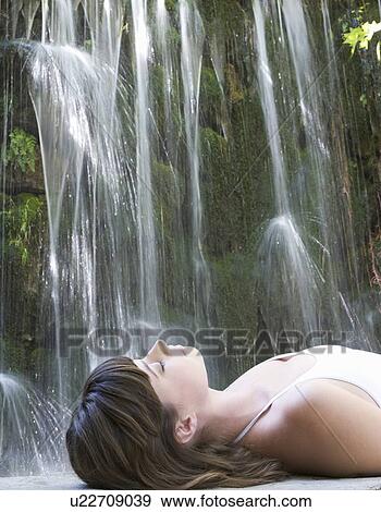 Stock Photo - A woman relaxing by a waterfall. Fotosearch