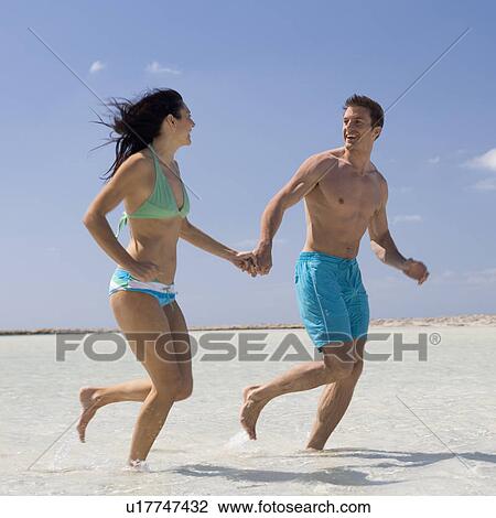 A couple running on a beach View Large Photo Image Stock Image - A couple running on a beach. Fotosearch