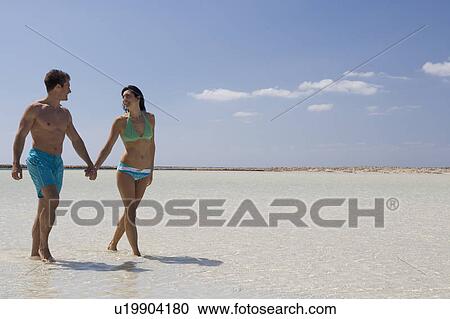 Stock Image - A couple walking on a beach. Fotosearch
