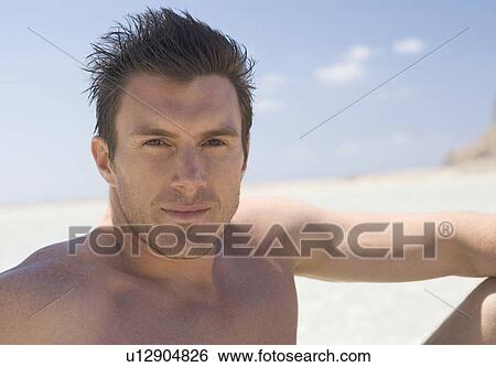 Stock Photograph - Portrait of a man sitting on a beach. Fotosearch