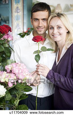 Couple choosing flowers in a florist's shop, red roses View Large Photo Image Stock Photo - Couple choosing flowers in a florist's shop, red roses. Fotosearch