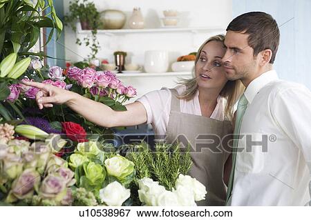 Florist helping male customer to choose some flowers View Large Photo Image Stock Photo - Florist helping male customer to choose some flowers. Fotosearch