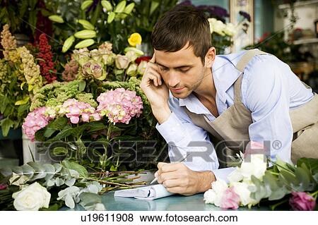 Male florist at the shop counter, taking an order over the telephone View Large Photo Image Stock Photo - Male florist at the shop counter, taking an order over the telephone. Fotosearch