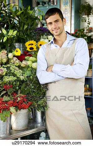 Picture - Male florist standing amongst the flowers in his shop. Fotosearch