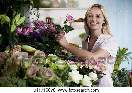 Stock Photo - Woman florist in her shop, surrounded by an assortment of flowers. Fotosearch